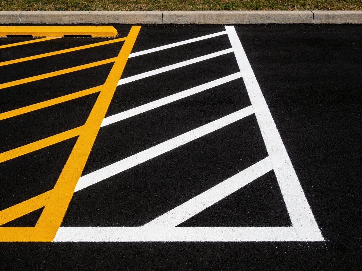 Freshly painted white parking stall lines on newly sealed black asphalt